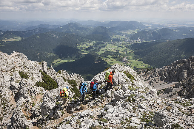 Wanderergruppe auf felsigem Bergpfad mit Panoramablick ins alpine Tal