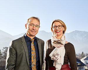 Smiling business professionals standing outdoors with snowy mountains in background